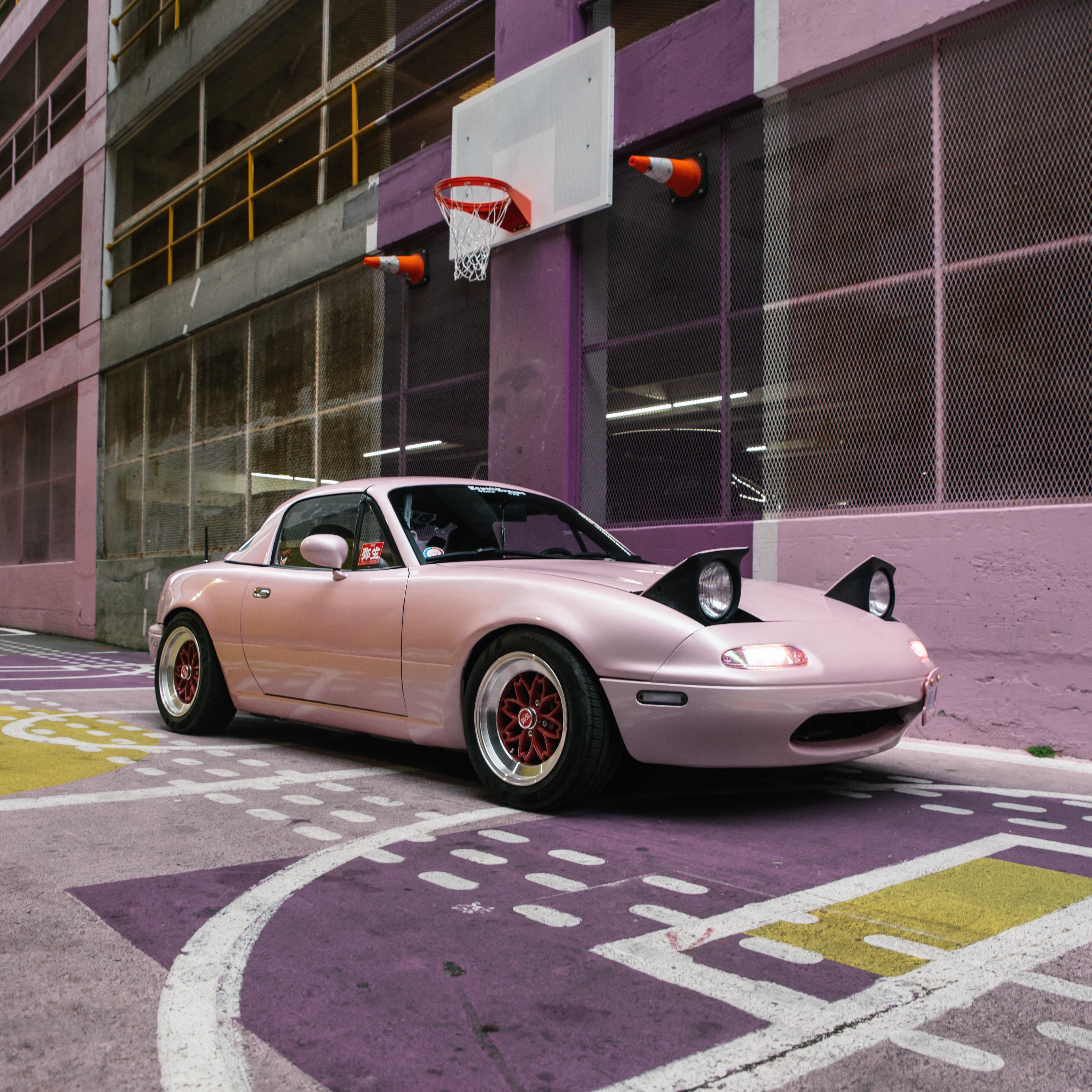 pink mx5 mazda miata in a colorful alleyway in vancouver on hayashi yayoi wheels with heart shaped lights. Famous car from tiktok